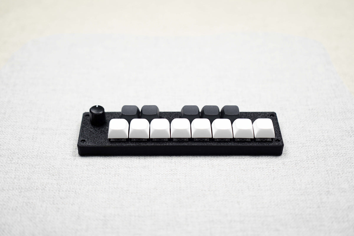 The ParksTool 13KS-1ES at an angle on a linen surface: eight white keys along the front, five black keys behind them, and an encoder knob at the left end